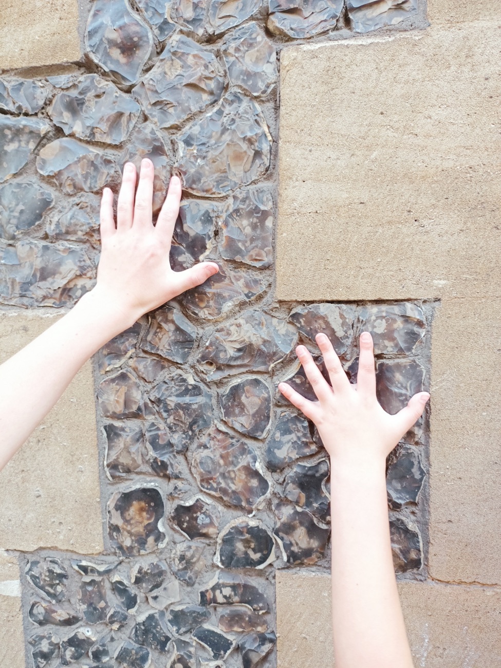 Hands resting on the flint wall of Southwark Cathedral, London